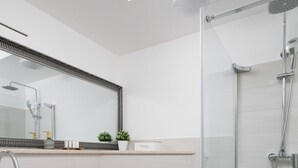 Une salle de bain moderne avec une douche à parois de verre, un lavabo blanc et des toilettes.