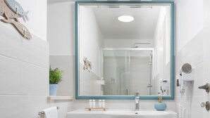 Une salle de bain avec un lavabo blanc, un miroir bleu et un sèche-cheveux fixé au mur.