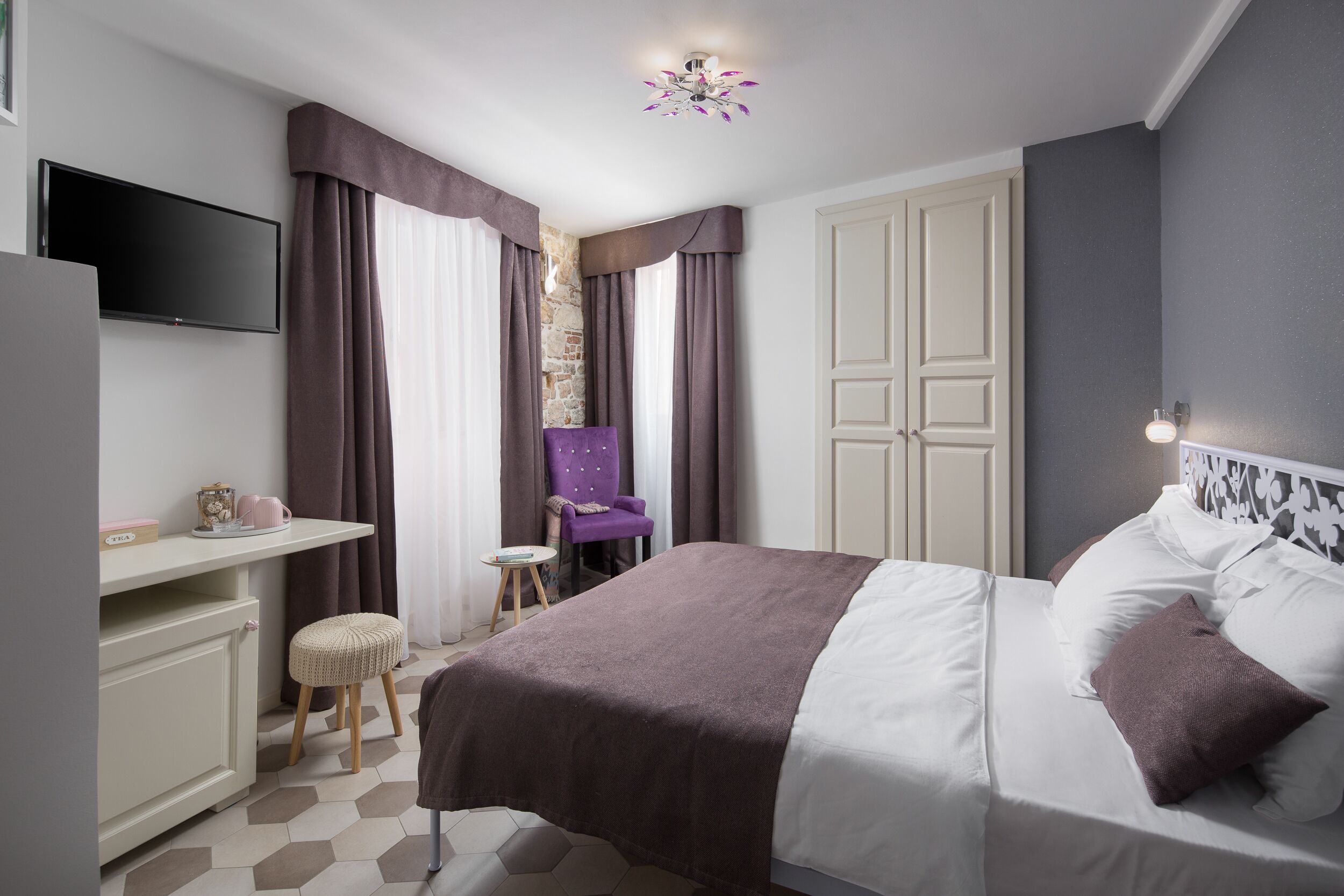 Een slaapkamer met een bed, een bureau, een stoel en een televisietoestel.