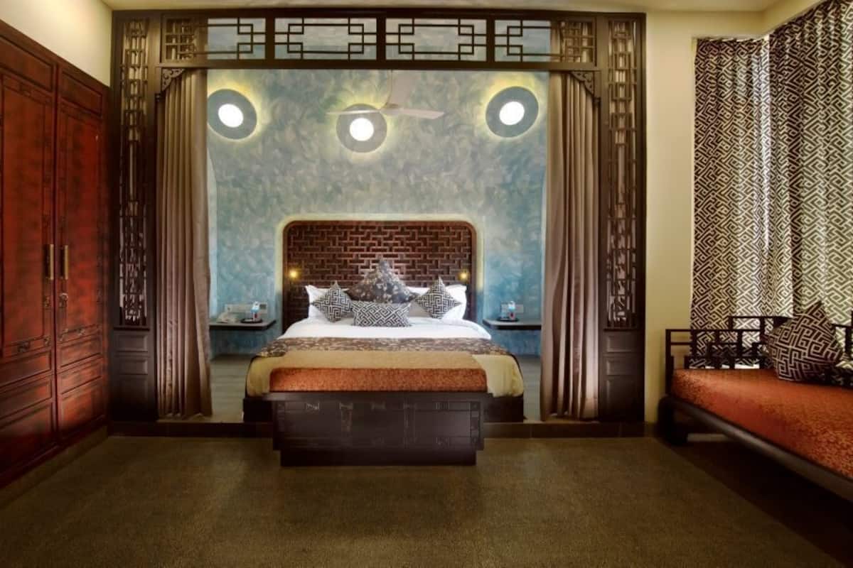 A bedroom with a large bed, a wooden wardrobe, and a patterned curtain.
