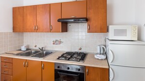 Eine Küche mit Holzausstattung, einem Gasherd, einer Mikrowelle und einem Kühlschrank.