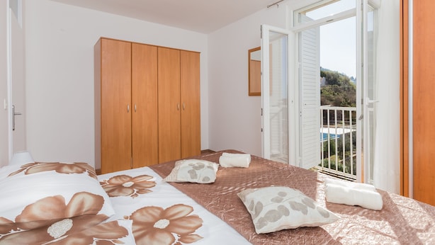 Ein Schlafzimmer mit Bett, Holzschrank und einem Balkon mit Blick.