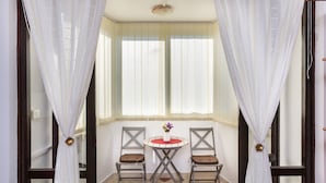 Ein Zimmer mit zwei Stühlen und einem kleinen Tisch mit Blumen.'