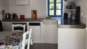 A kitchen with a white table, chairs, a sink, and a window with a blue door.