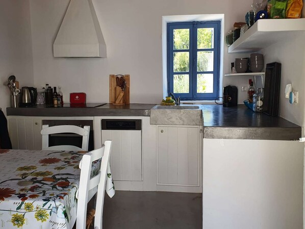 A kitchen with a white table, chairs, a sink, and a window with a blue door. - 2 Tiny houses for 2 couples or Family (Karavas)
