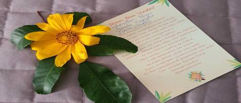 A card with text and a yellow flower on a textured surface.