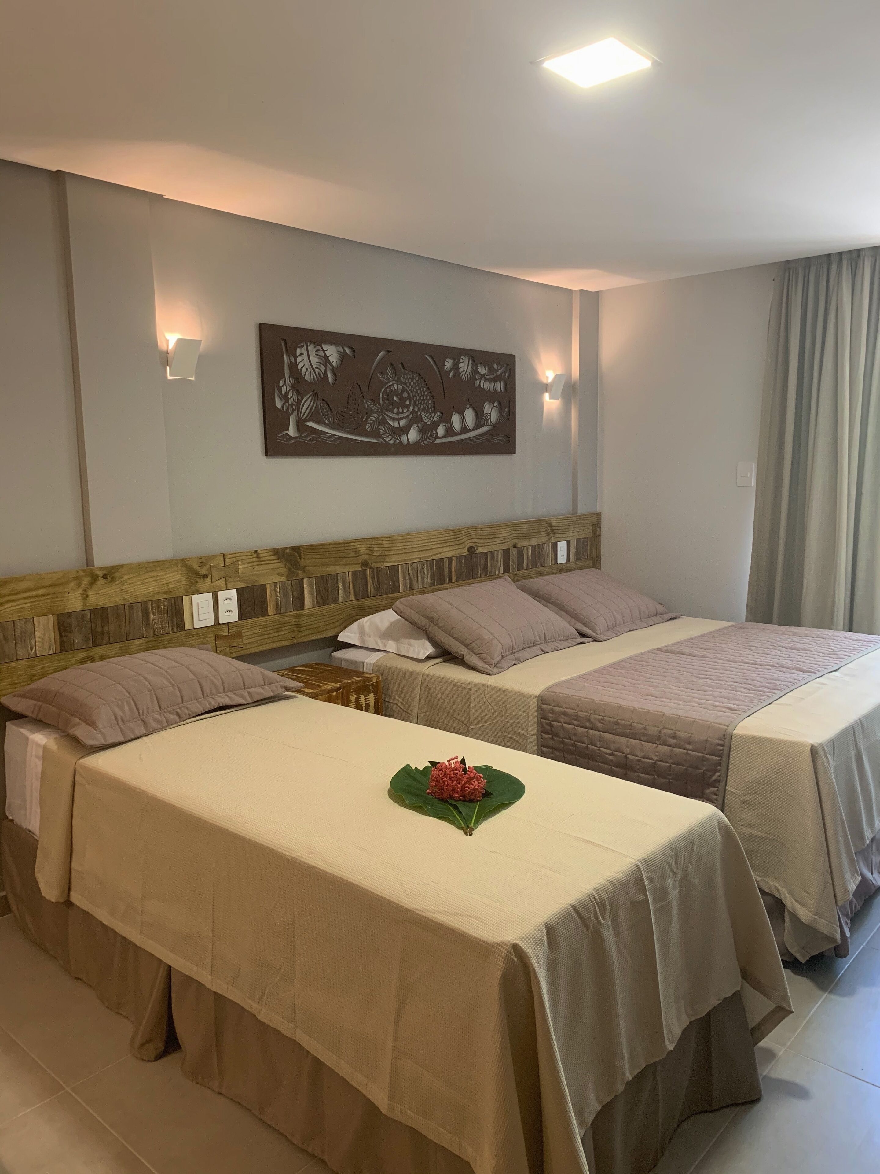 A hotel room with two beds, a wooden headboard, a wall-mounted artwork, and a small table with a decorative item.