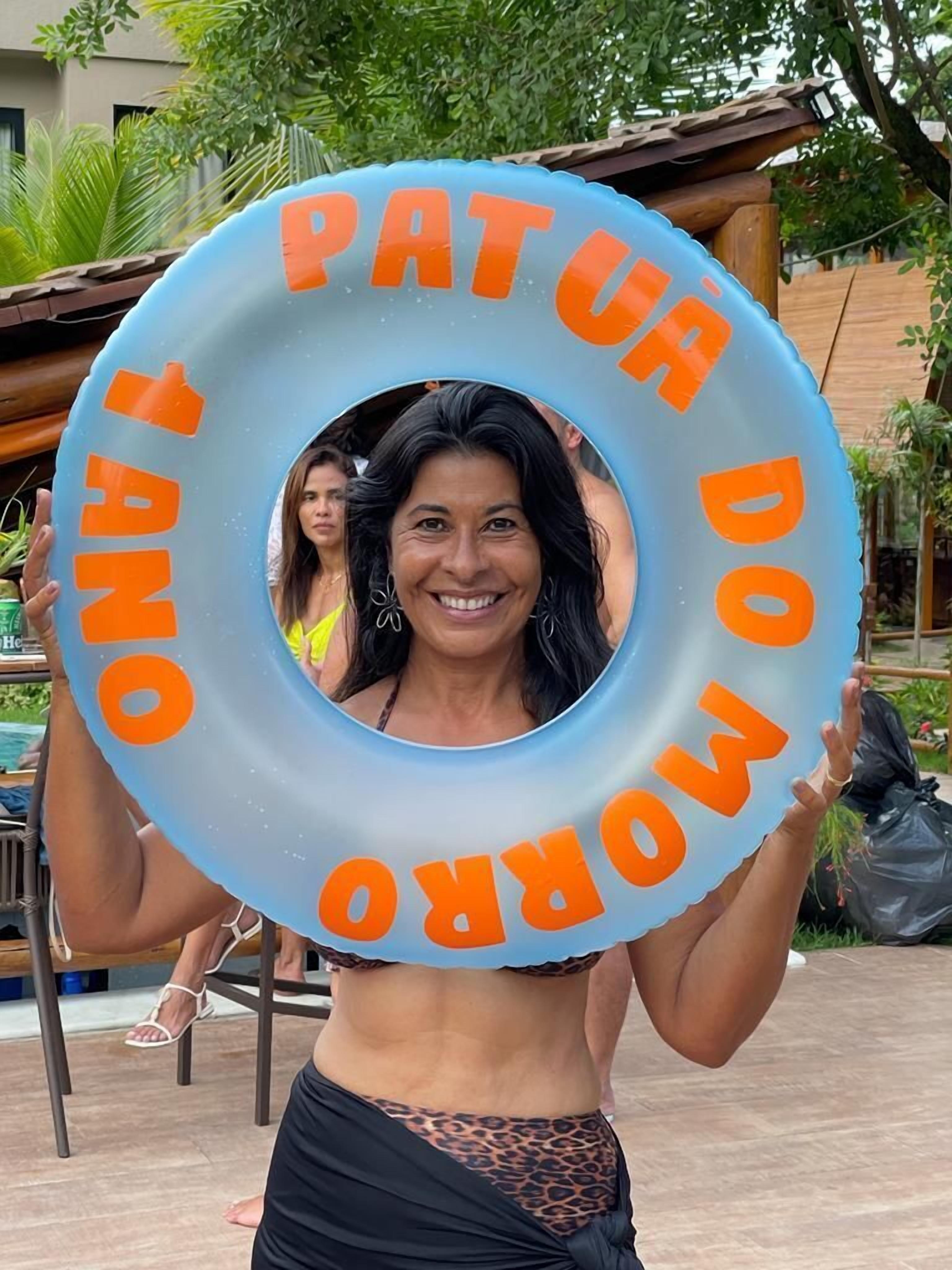 Eine Person hält einen blauen Schwimmreifen mit dem Schriftzug 'PATAU DONO'.