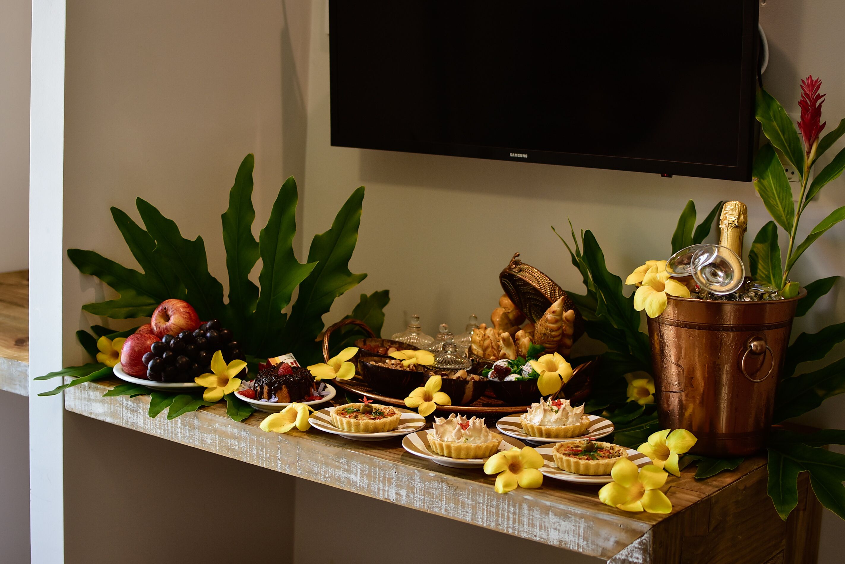 A buffet table with various desserts, fruits, and a champagne bucket.