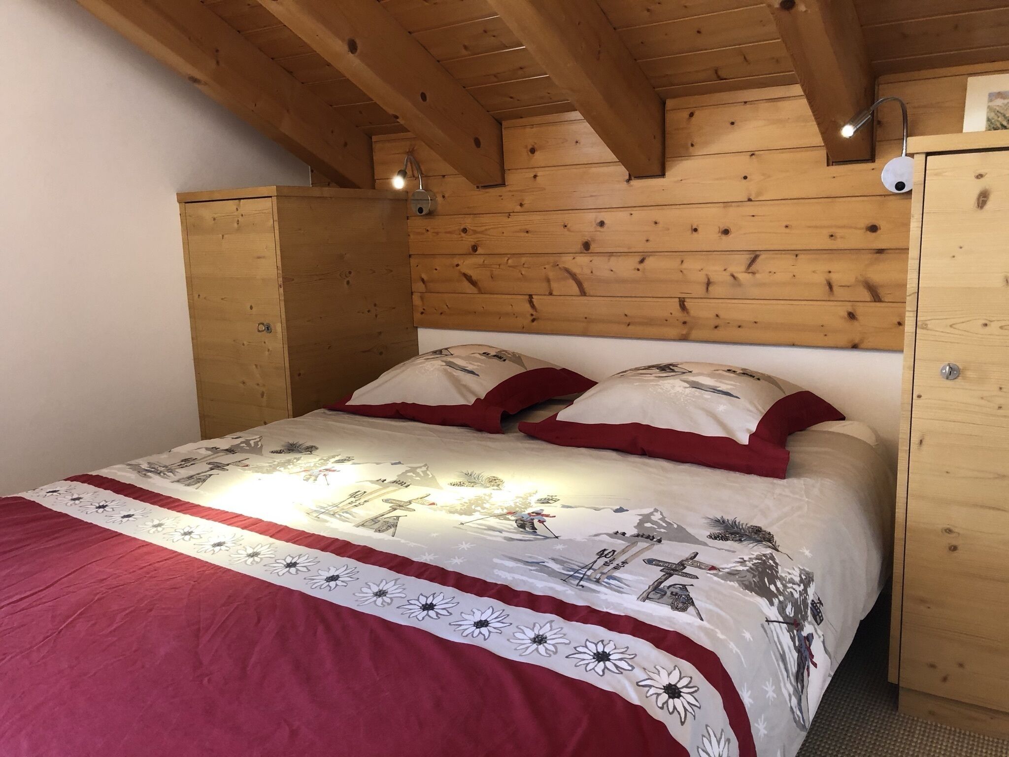 A wooden-paneled bedroom with a bed, pillows, and a nightstand.