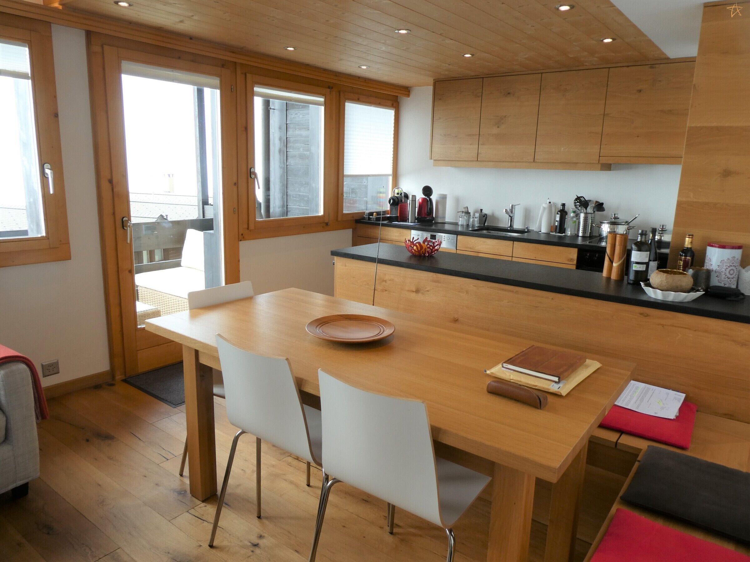 A modern kitchen with wooden cabinets, a dining table, and chairs.