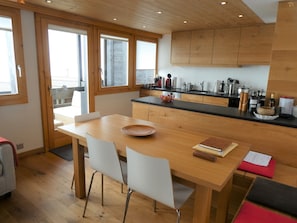 A modern kitchen with wooden cabinets, a dining table, and chairs.
