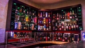 A bar with multiple shelves of liquor bottles and glasses. - Excel Oriental Hotel & Suites (Lagos)