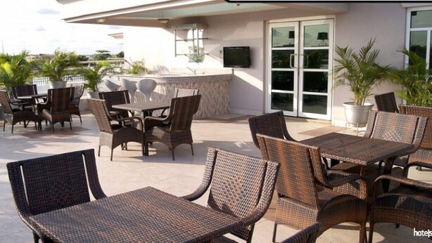 An outdoor patio with wicker furniture and a view of the city. - Excel Oriental Hotel & Suites (Lagos)