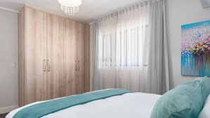 Un dormitorio con una cama grande, un armario y un cuadro en la pared.
