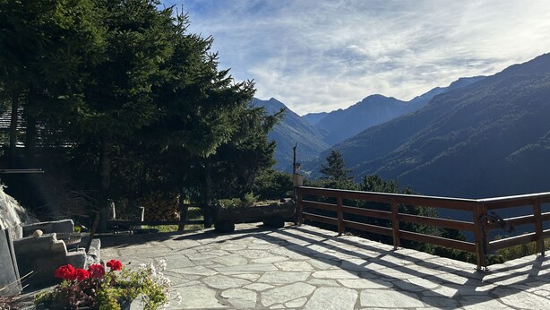 A stone patio with a wooden railing overlooking a mountainous landscape.