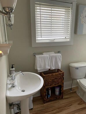 Une salle de bain avec un lavabo, des toilettes et une fenêtre équipée de stores.