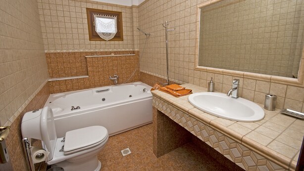 A bathroom with a bathtub, toilet, sink, and a mirror. - Villa Manolia (Alonissos)