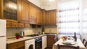 Een keuken met houten kastjes, een wasmachine, een fornuis en een eettafel voor vier personen.