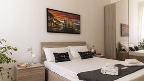 Een moderne hotelkamer met een groot bed, een nachtkastje, een spiegel en een schilderij van een stadsgezicht.