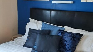 A bed with a blue headboard, white bedding, and multiple pillows. - 3 bed Caravan Approx 10 Mins From Beach Bill 1 (Hull)