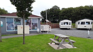 A campsite with a picnic table, a small building with a sign, and a fenced area. - 3 bed Caravan Approx 10 Mins From Beach Bill 1 (Hull)