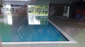 An indoor swimming pool with clear water, tiled floor, and a view of greenery outside. - 3 bed Caravan Approx 10 Mins From Beach Bill 1 (Hull)