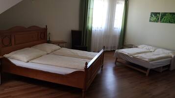 A bedroom with two wooden beds, a nightstand, a lamp, and a window with green curtains.
