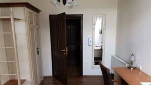 A room with a wooden floor, a white wardrobe, a wooden desk, and a door leading to another room. - Hanfthal-Hof (Laa an der Thaya)