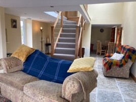 A living room with a sofa, a chair, a staircase, and a dining area.