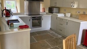 A kitchen with a stove, oven, microwave, and cabinets. - Cosy 2-bed Cottage With Garden Near Carlisle (Carlisle)
