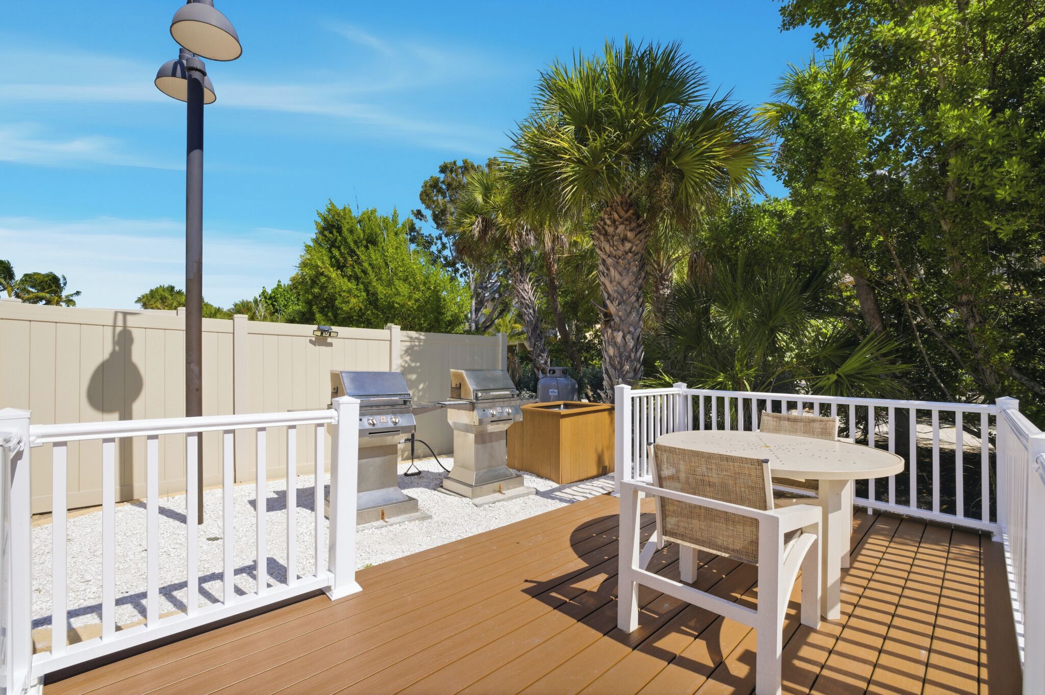 An outdoor patio with a grill, seating, and a lamp.