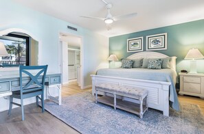A bedroom with a bed, a desk, a chair, and a ceiling fan.
