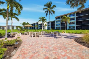 A hotel courtyard with outdoor seating, palm trees, and a building with multiple balconies.
