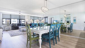 Un salon spacieux dotĂ© dâune grande fenĂȘtre, dâun canapĂ©, dâune table basse et dâun coin repas avec une table blanche et des chaises de couleur turquoise.