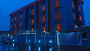 A multi-story hotel with a red and blue facade, multiple balconies, and a covered parking area. - Six Diamond Hotel (Lagos)
