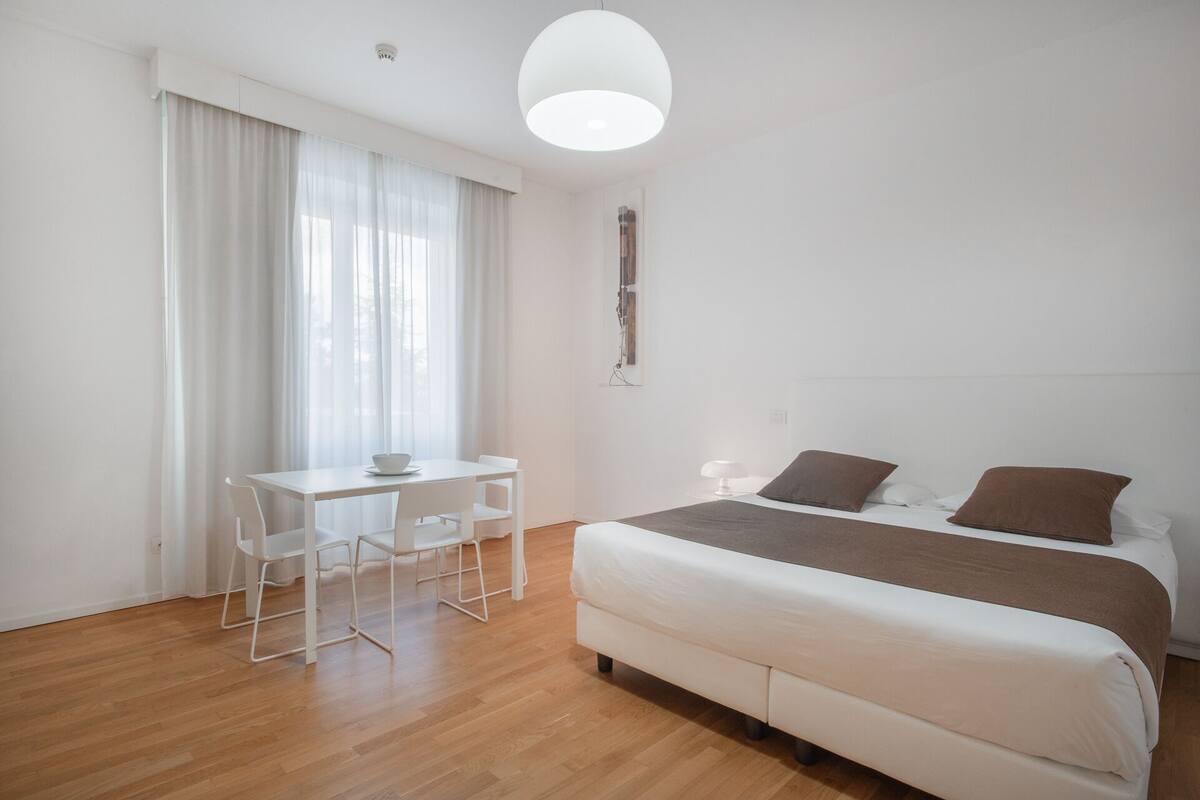 A minimalist bedroom with a bed, a desk, and a chair.