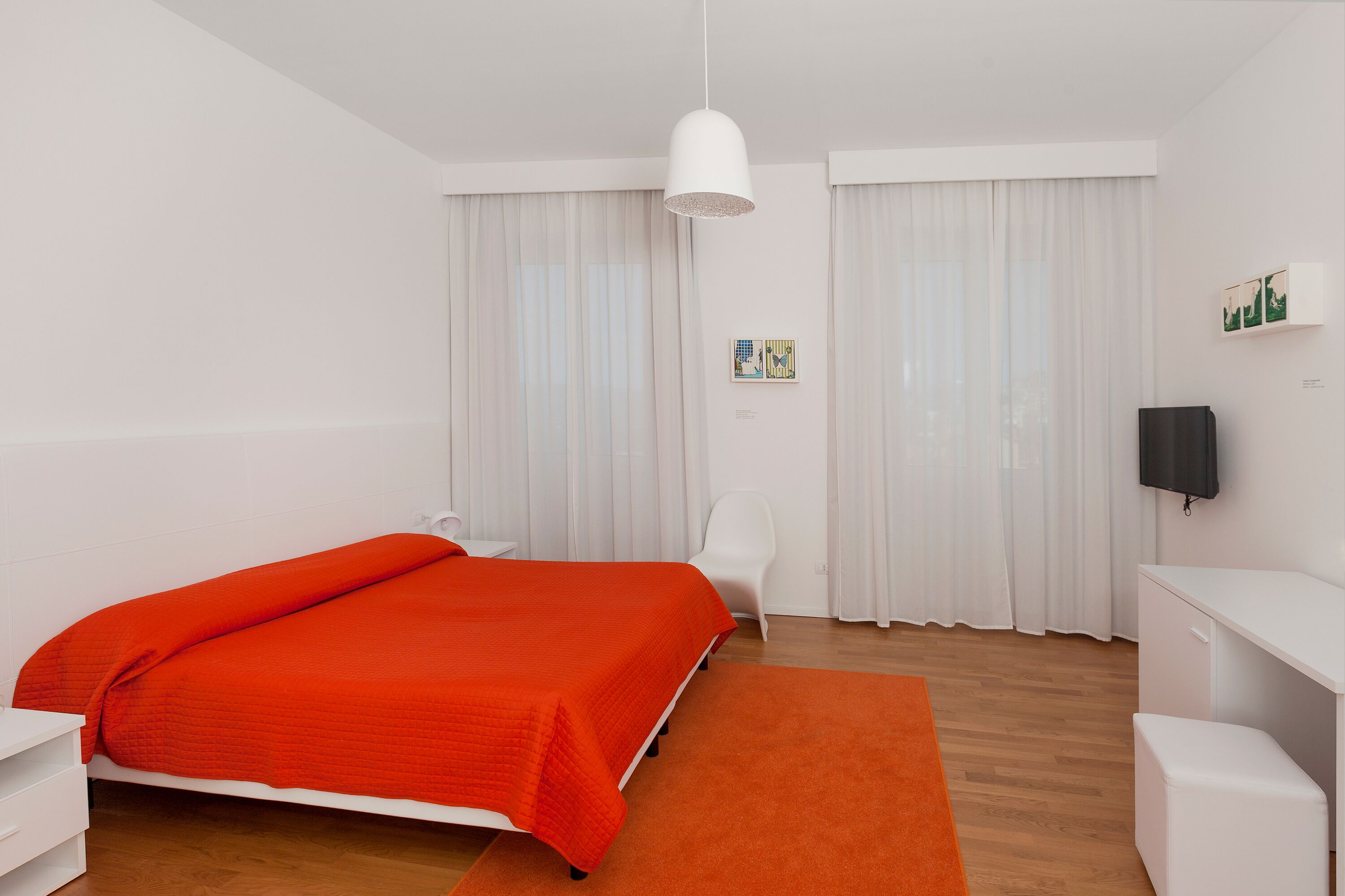 A modern bedroom with a large bed, a desk, and a chair.