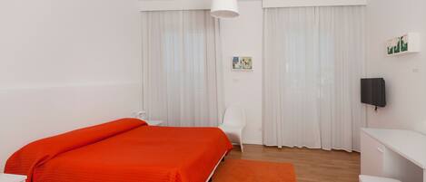 A modern bedroom with a large bed, a desk, and a chair.