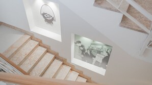A staircase with marble steps and white railings, leading to a landing with a framed black and white photograph. - Felix Hotels - Residence Grandi Magazzini (Nuoro)