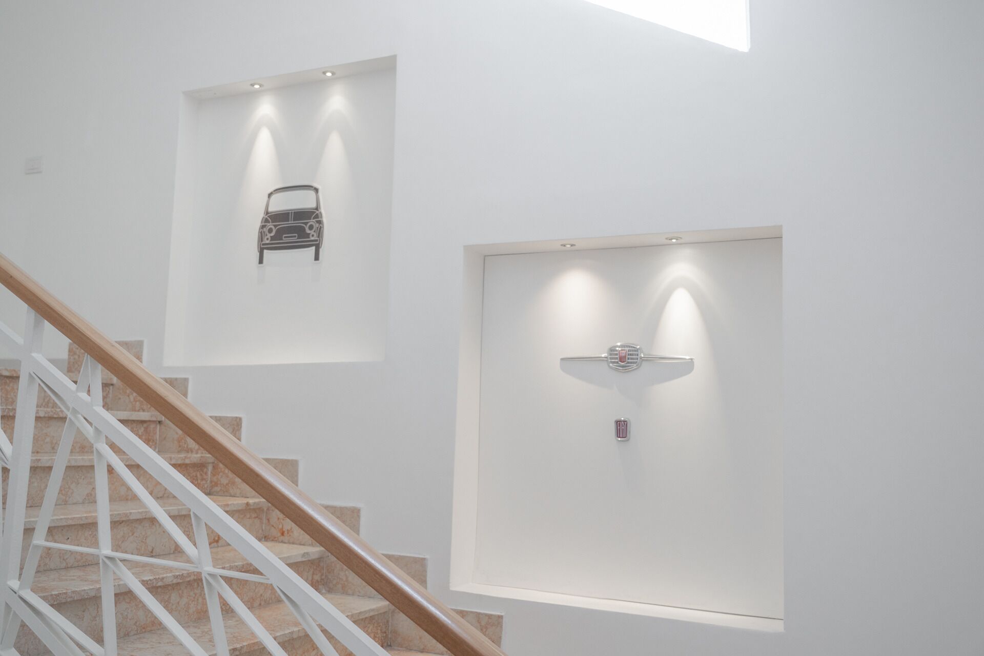 A staircase with white railings and a marble floor leading to a landing with recessed lighting.