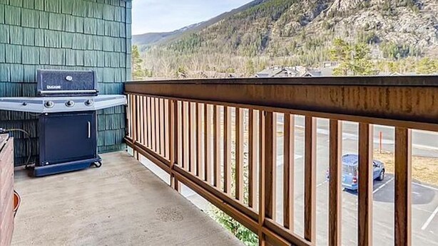 A balcony with a grill, a view of a parking lot, and a mountainous landscape. - Steps from Main St, quiet 2-bdrm condo w/views, fireplace, hot tub, steam shower (Frisco)