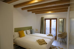 Une chambre d’hôtel avec deux lits, un balcon, une chaise et une vue sur l’extérieur.