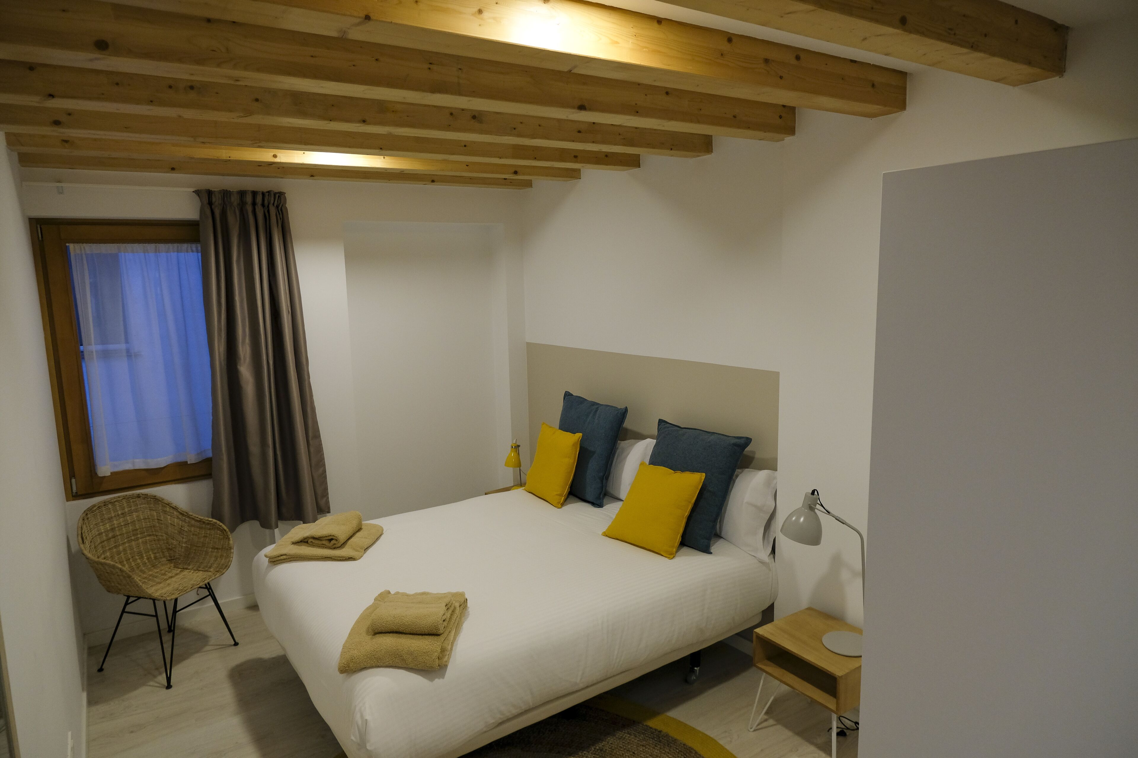 Un dormitorio con cama, una silla, un escritorio y una lámpara.