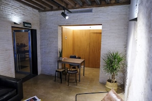 Un intérieur moderne avec un mur en briques, une porte en bois, une table avec des chaises et une plante en pot.