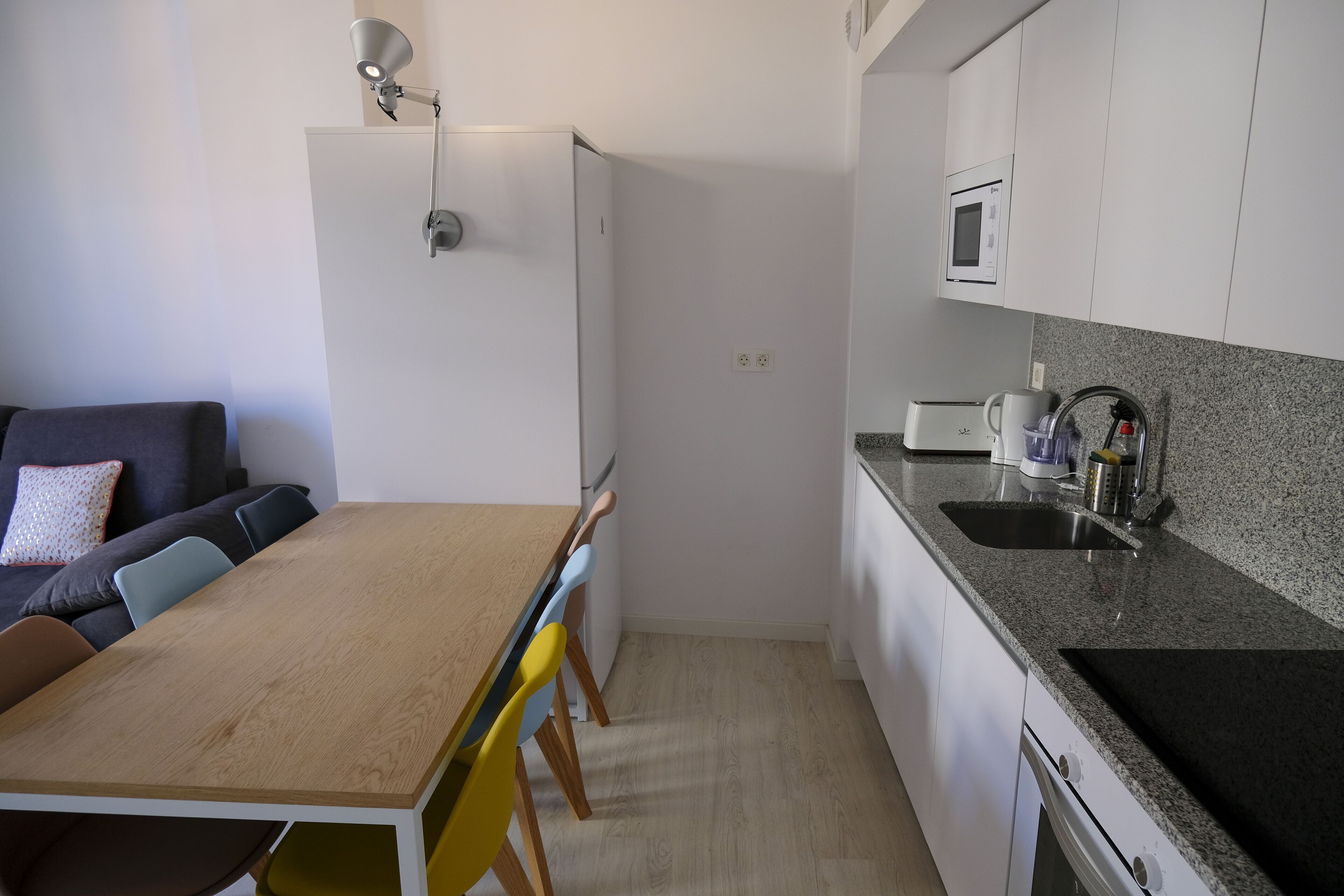Una cocina compacta con una mesa de madera, sillas, un microondas y un lavabo.