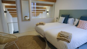 A bedroom with a large bed, a mirror, a wooden ceiling, and a rattan chair. - Silken Casa Platerias Siglo XV (Zaragoza)