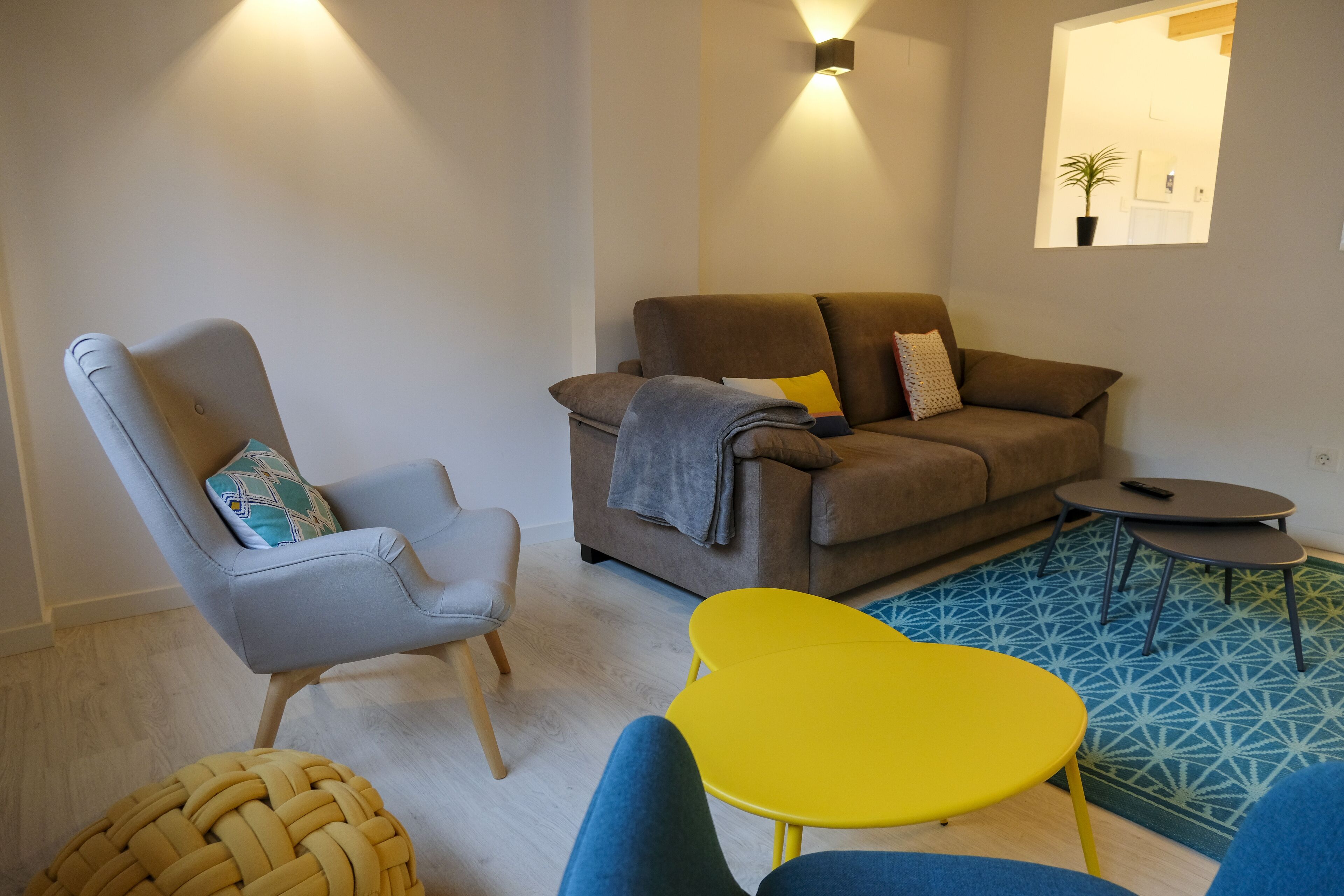 A modern living room with a grey armchair, a brown sofa, and a yellow table.