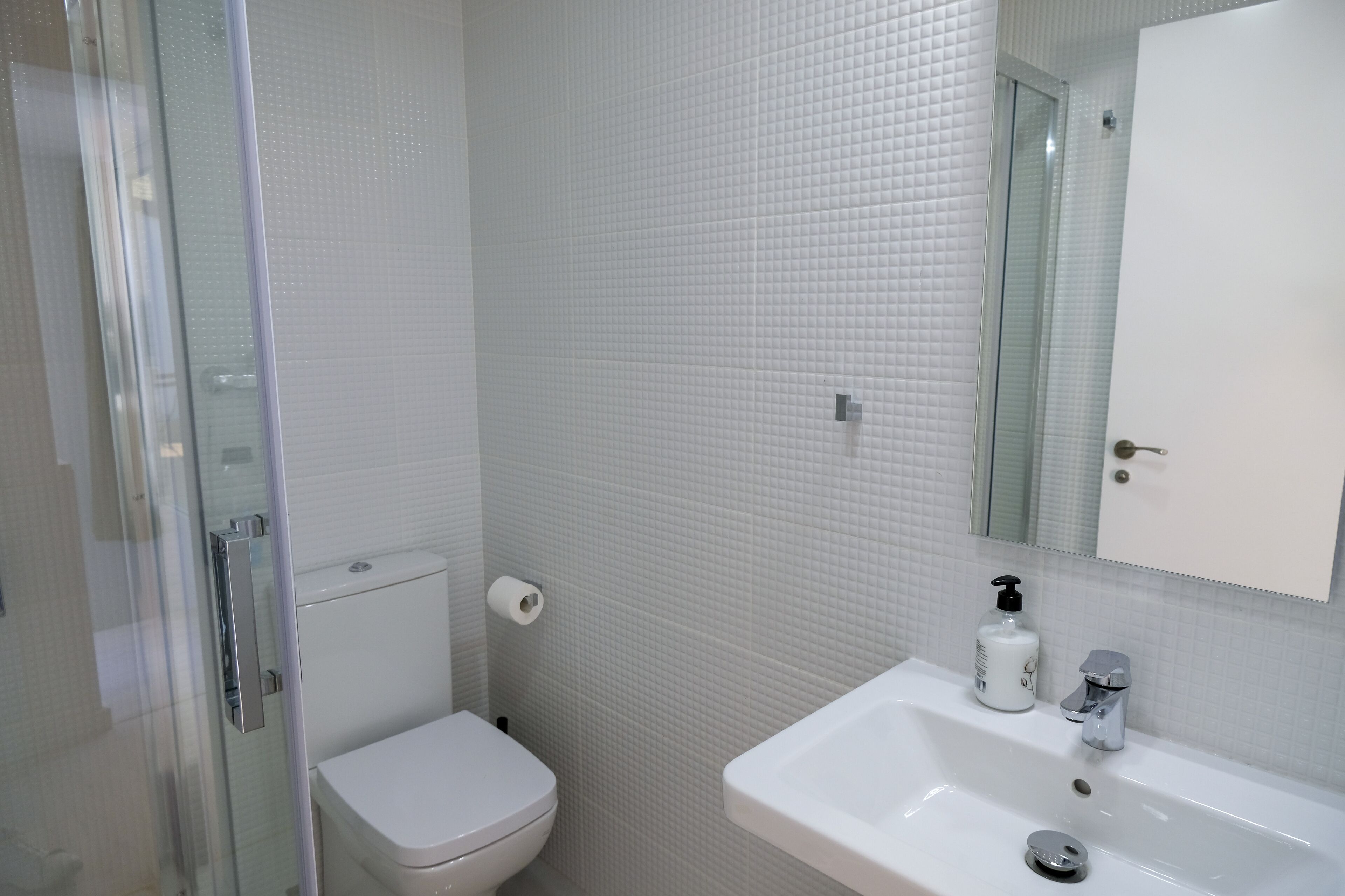 Un baño con inodoro, lavabo y cabina de ducha de vidrio.