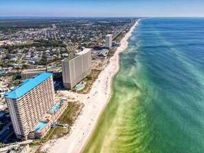 A coastal cityscape with a beachfront hotel featuring multiple floors, a swimming pool, and a beach area.
